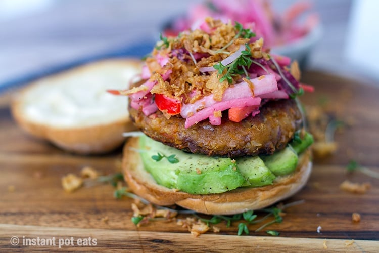 Vegan bean burgers on a bun with avocado, slaw and pickled onions