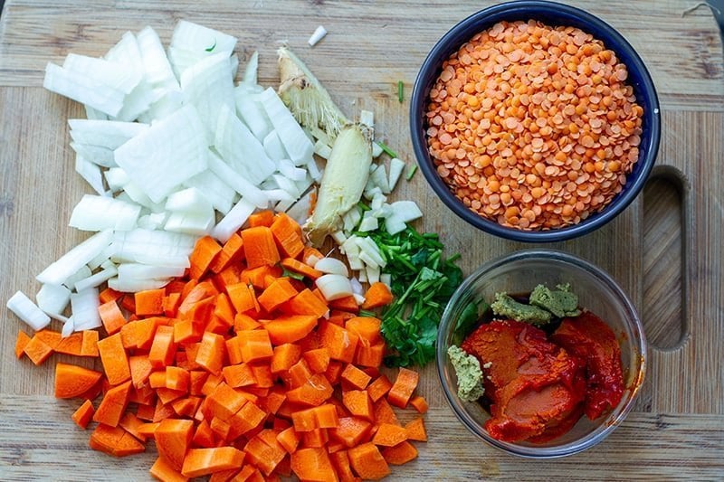 Instant Pot red lentil soup ingredients: onions, ginger, garlic, carrots, lentils, curry paste, coriander