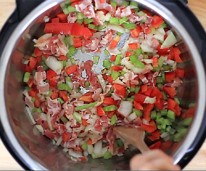 Sauteing onions, peppers, celery and bacon in the pot