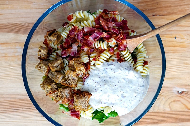 Mixing a pasta salad with Caesar dressing