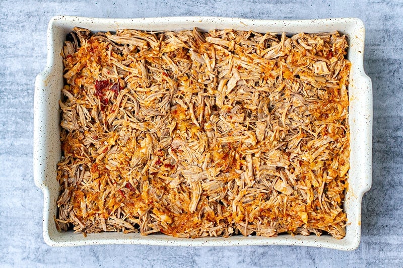 Shredded pork al pastor in a casserole dish