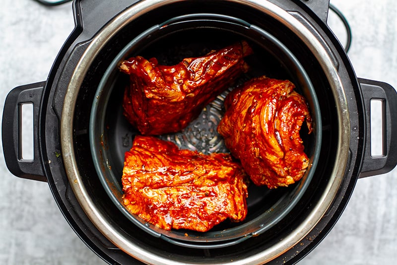 Air Fryer basket with pork ribs inside the Instant Pot