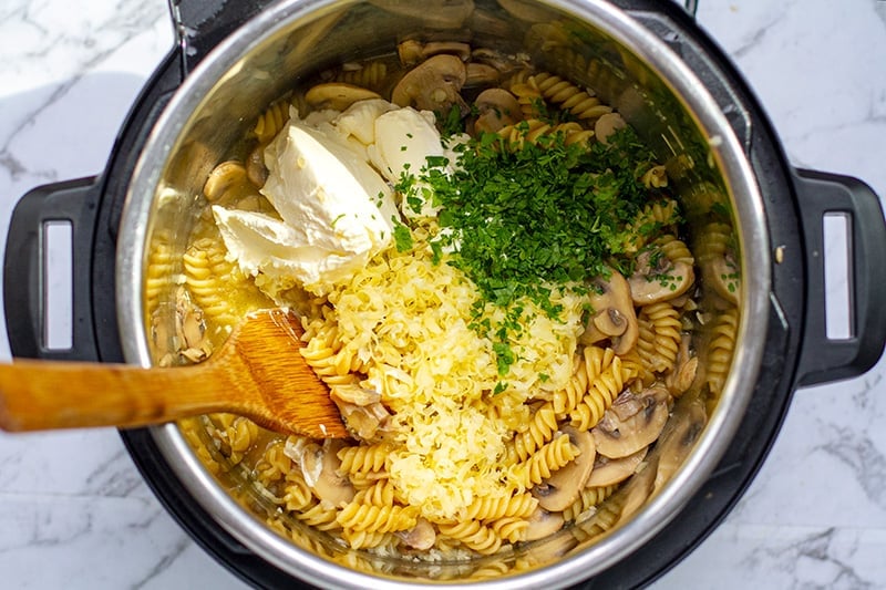 Adding cheese, sour cream and parsley to pasta in the Instant Pot