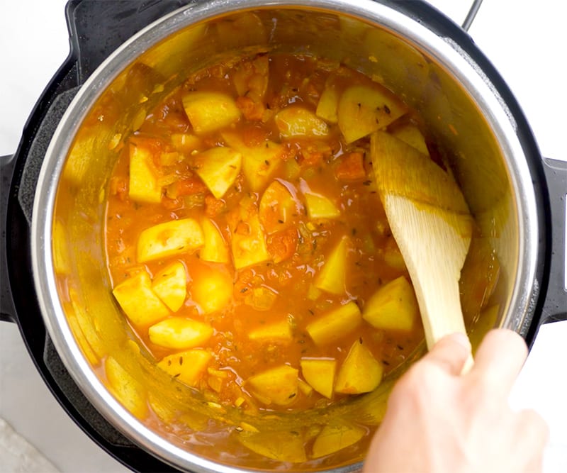 Potatoes stirred in tomato sauce for Aloo Gobi recipe