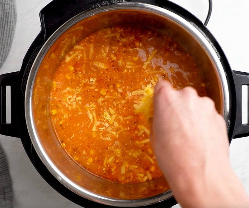 Stir in grated cheese into enchilada soup in Instant Pot
