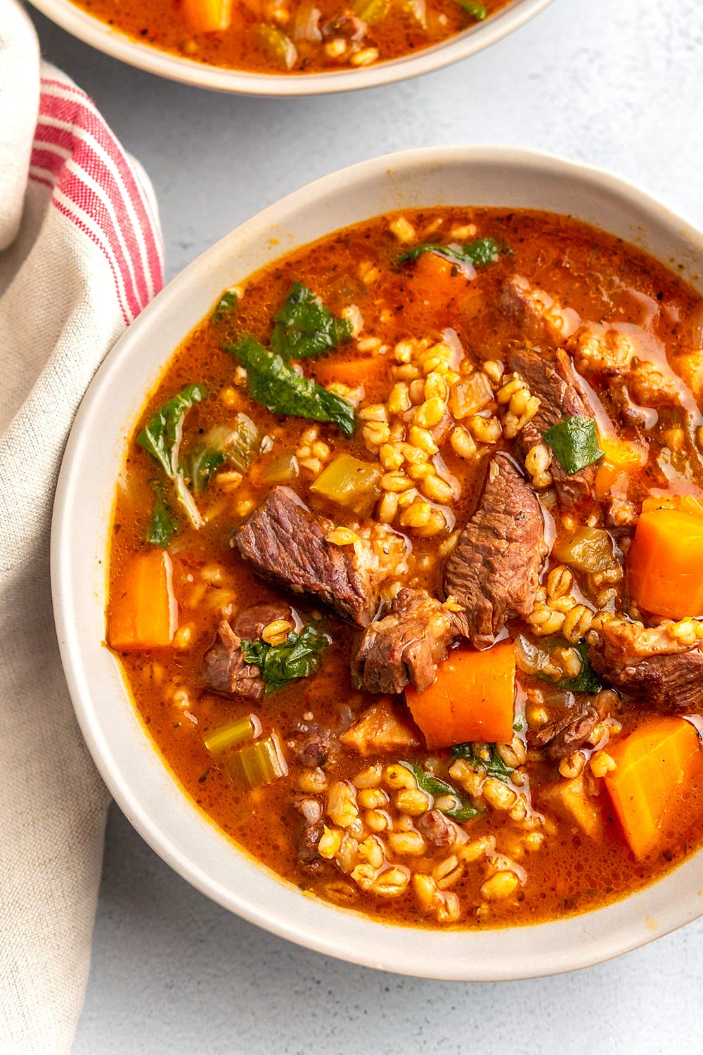 Beef & Barley Soup with carrots and basil pesto in a bowl.