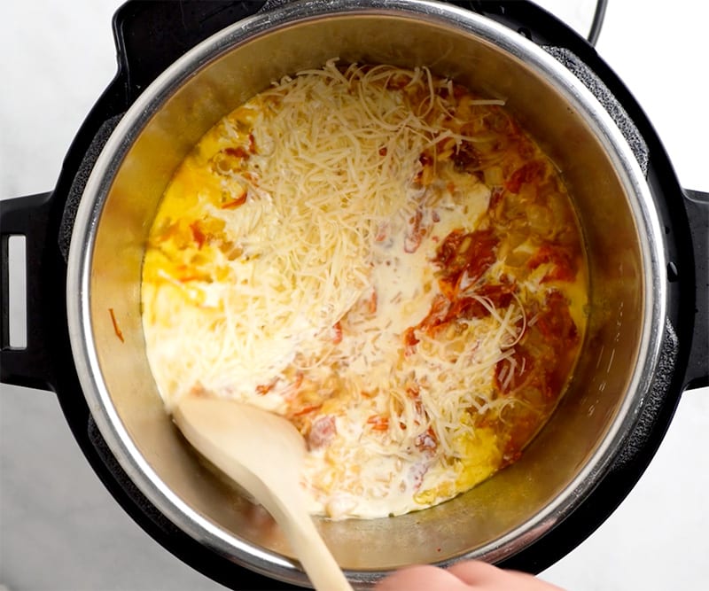 Stirring cream and Parmesan with cooked orzo in the Instant Pot