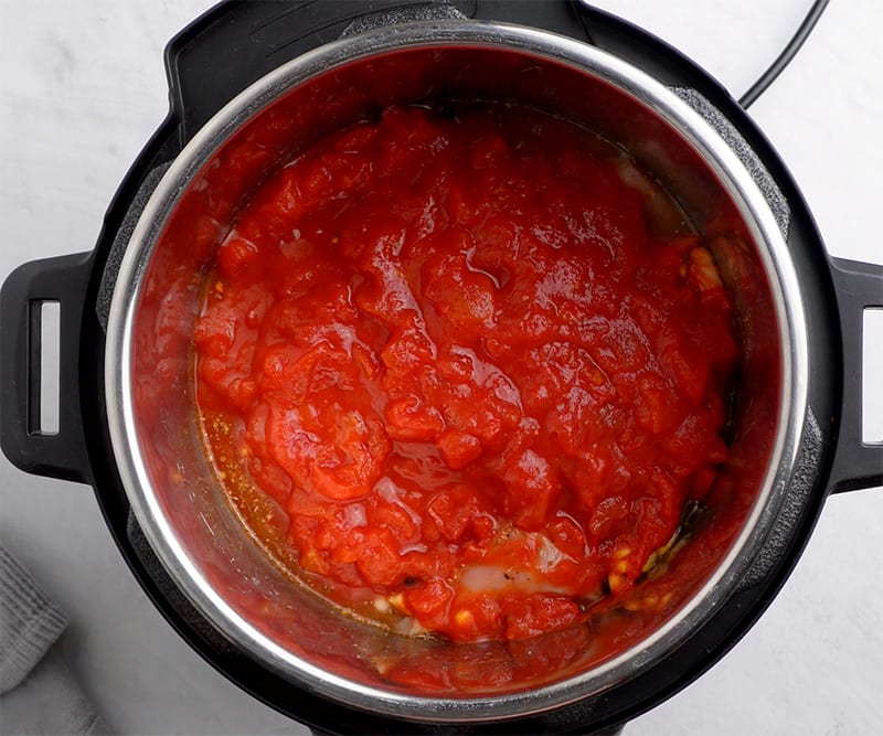 Spread the crushed tomatoes over the top but don’t stir through all the way.