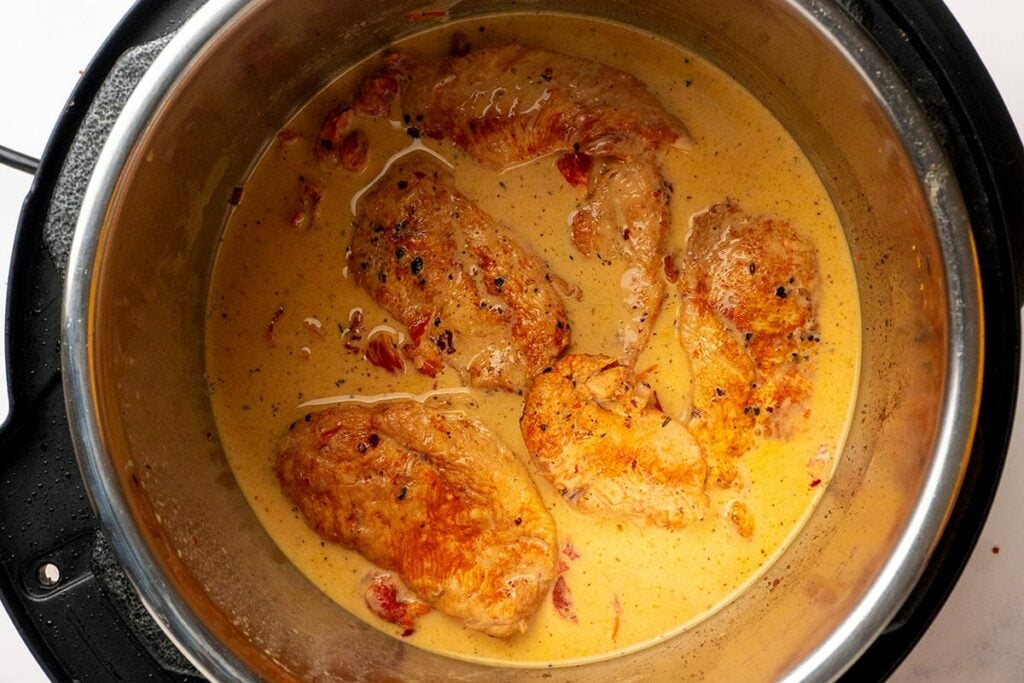 Chicken breasts after cooking nestled in the creamy sun-dried tomato sauce