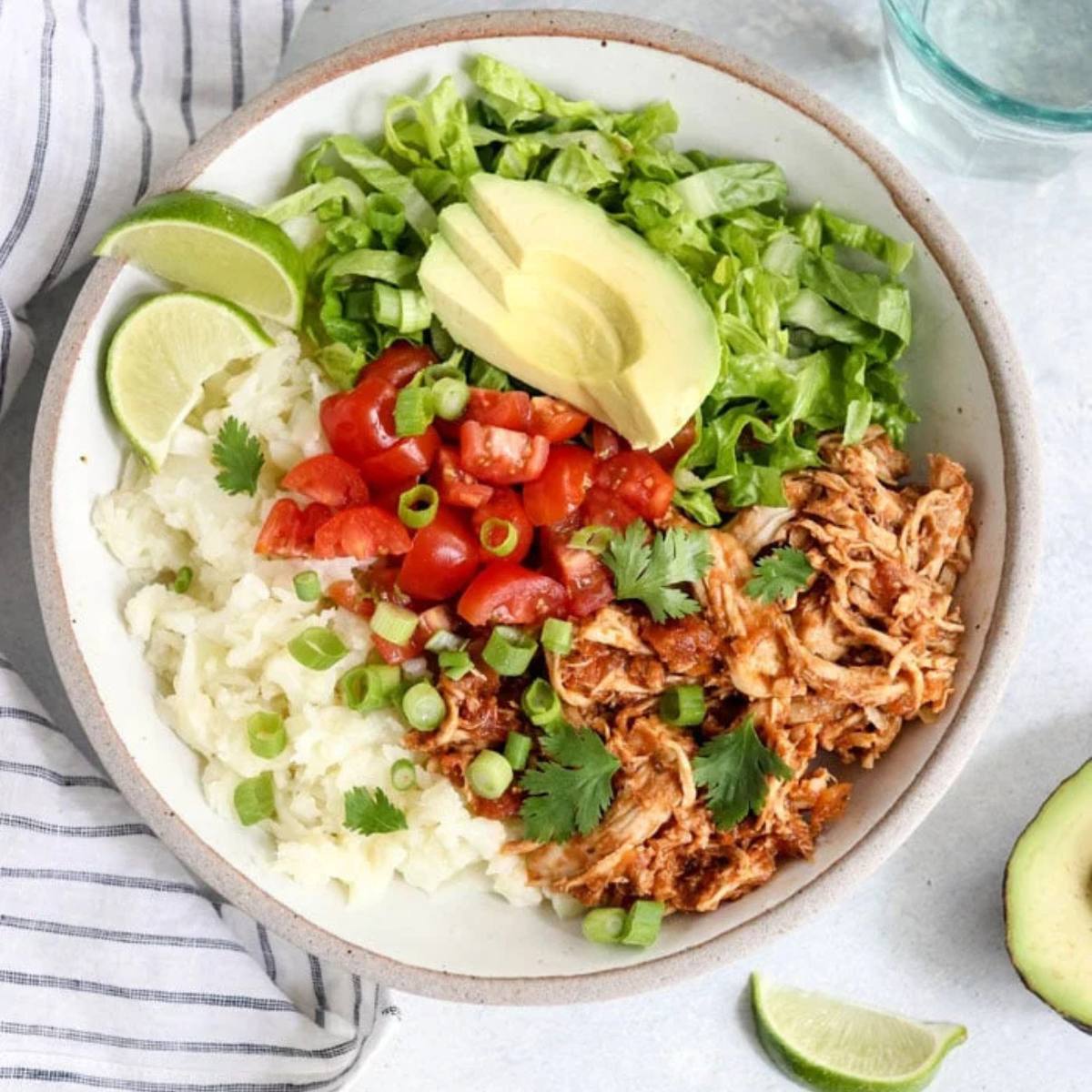 A nutritious Chicken Burrito Bowl with seasoned shredded chicken, cauliflower rice, avocado, salsa, and fresh veggies, perfect for a low-carb & Whole30 meal.