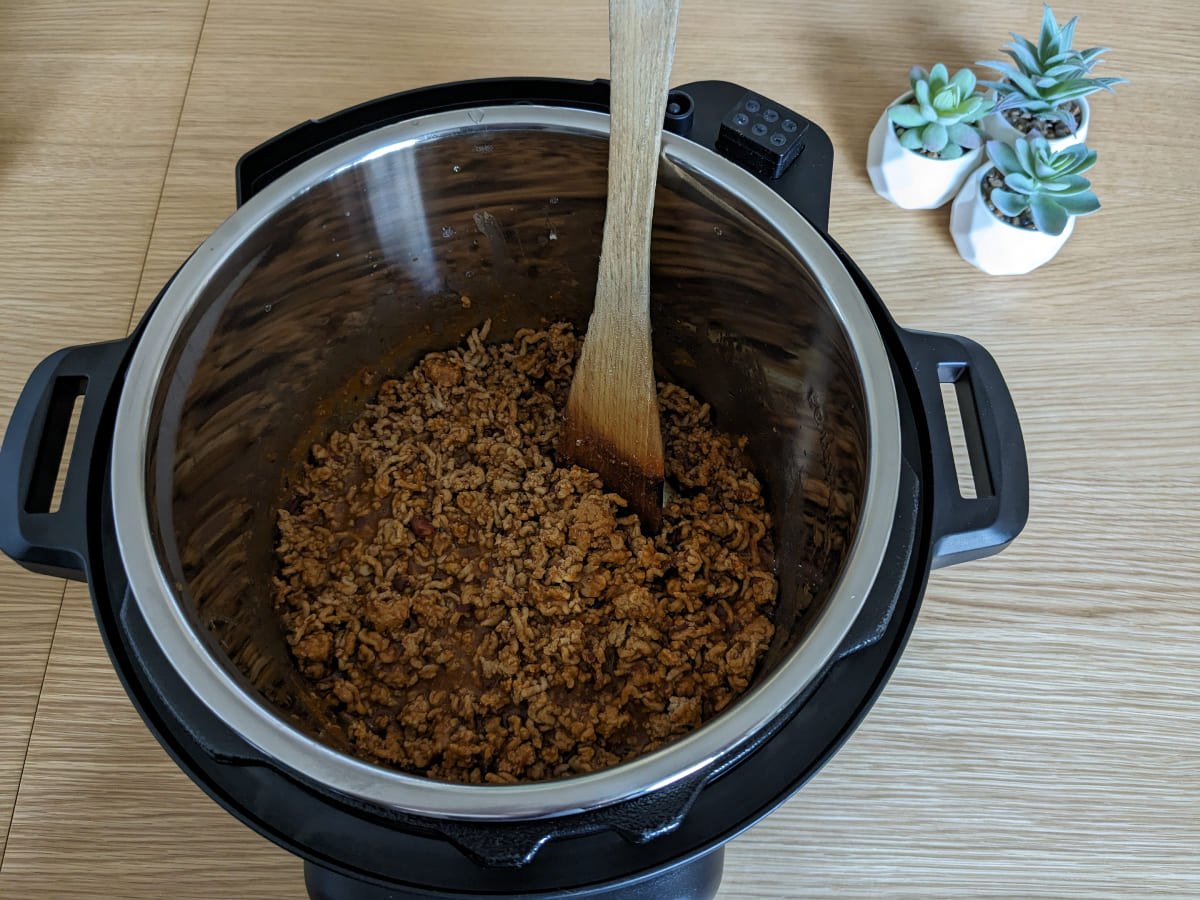 ground meat with wooden ladle inside Instant Pot