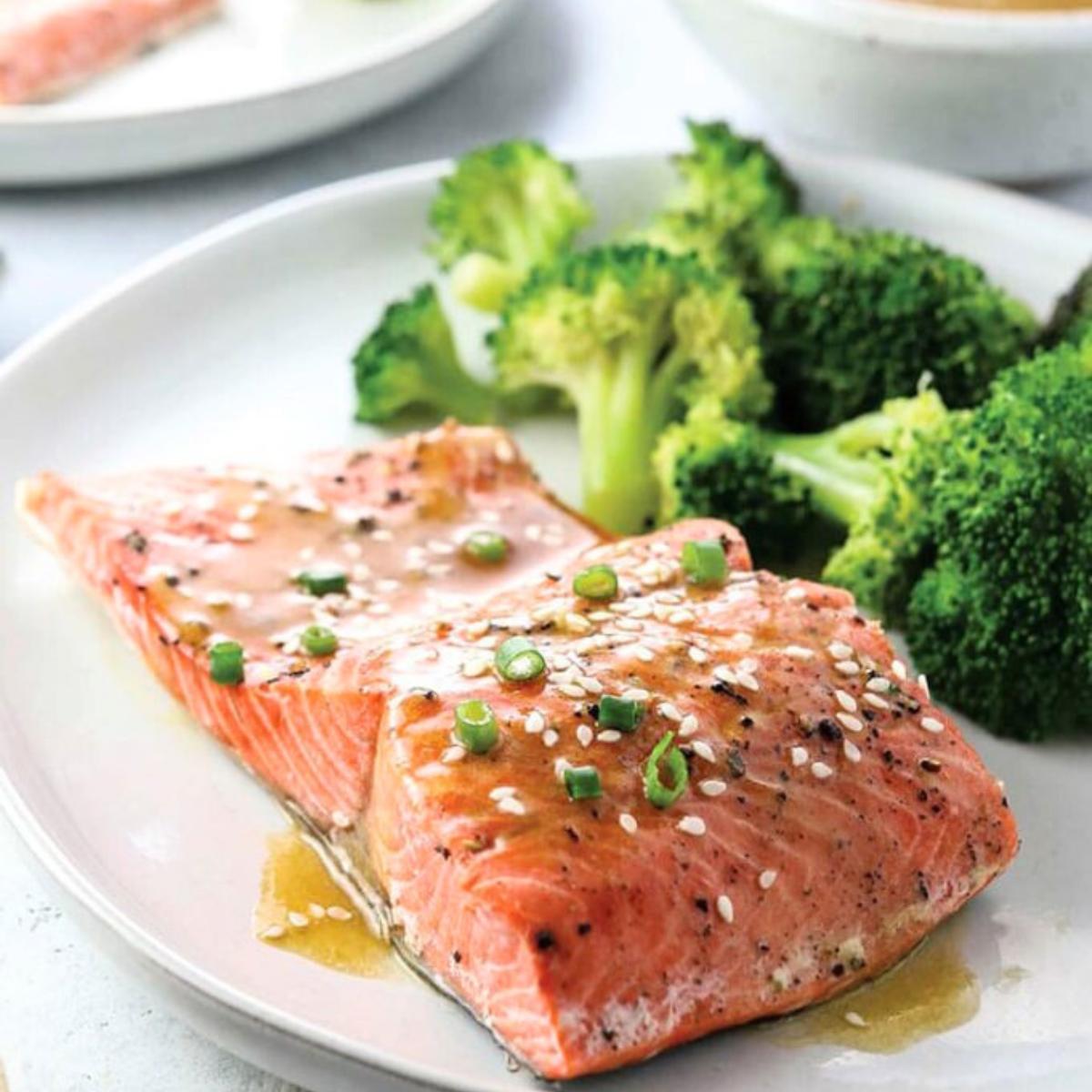 A flavorful Soy-Ginger Salmon with a glossy, caramelized glaze, served alongside tender, roasted broccoli and a sprinkle of sesame seeds.