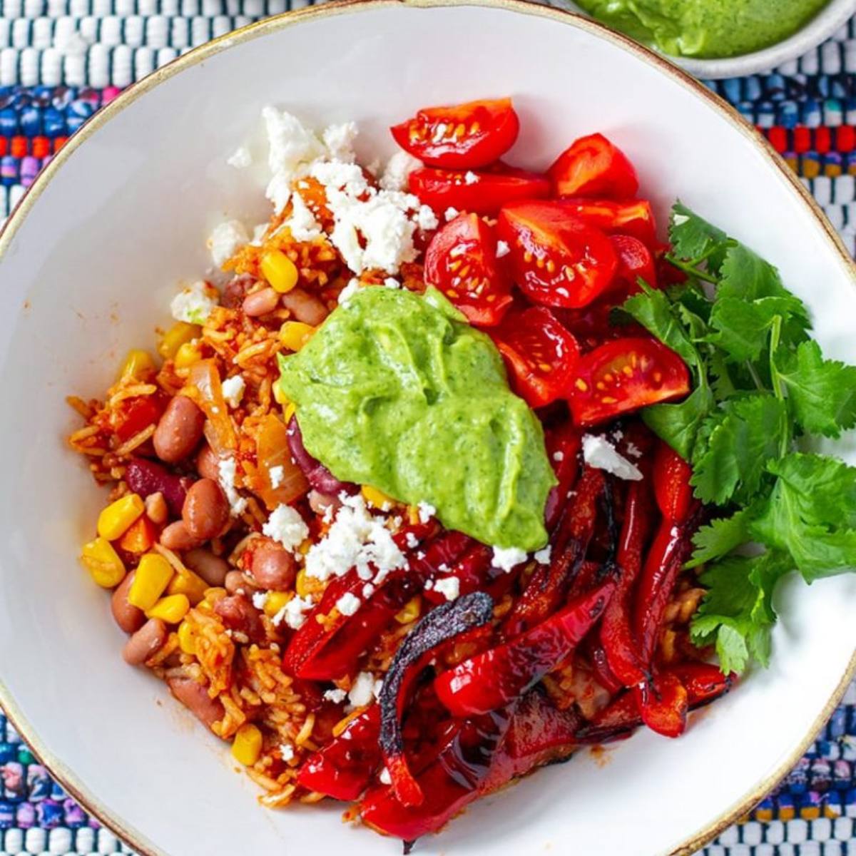 A vibrant Veggie Burrito Bowl with seasoned rice, black beans, roasted vegetables, and a creamy avocado crema, topped with fresh cilantro and lime.







