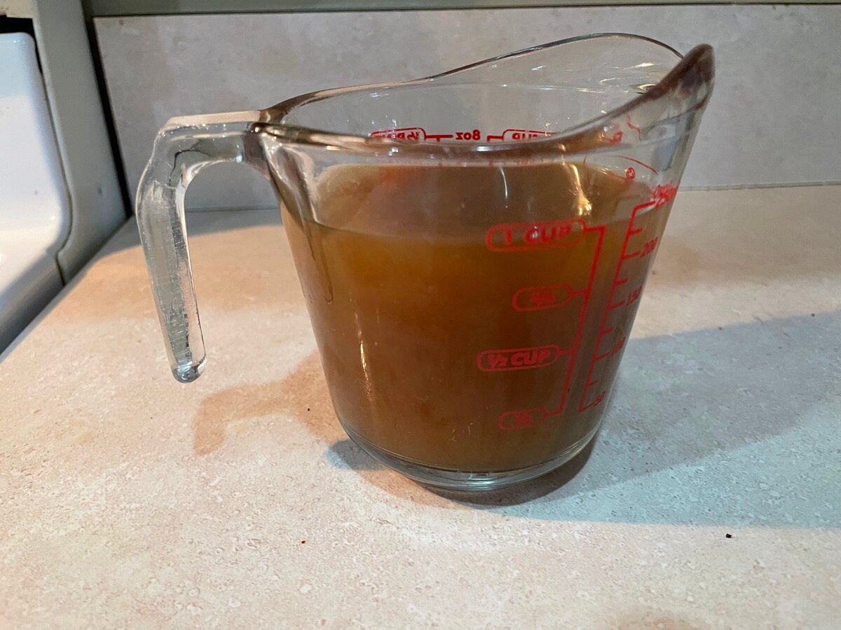 chicken bone broth in transparent measuring cup