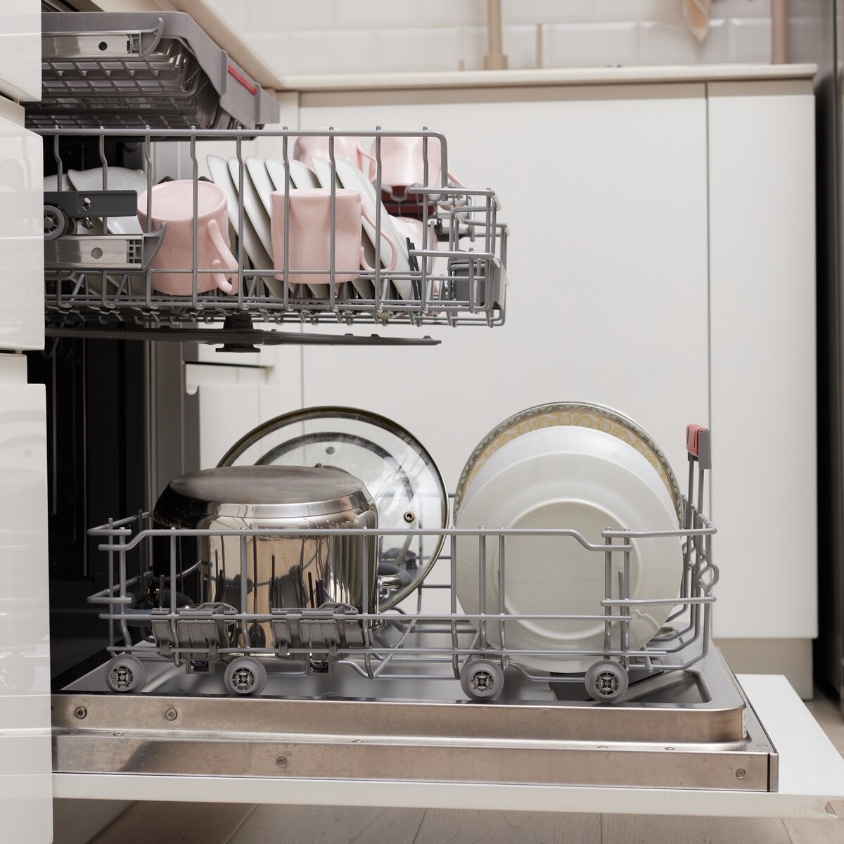 Open built-in dishwasher machine with clean cutlery, dishes