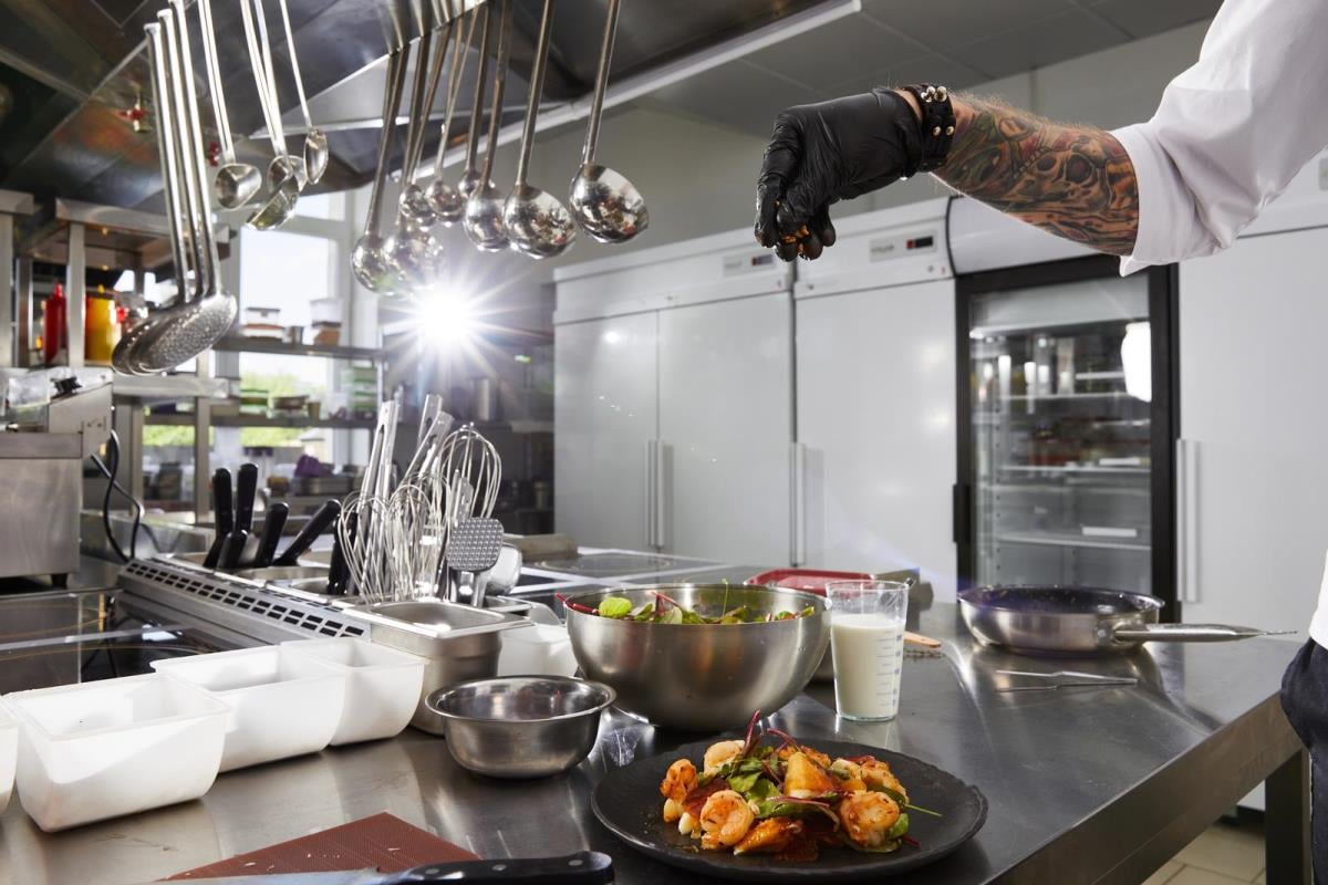 сlose-up of chef hands preparing salad in a restaurant kitchen