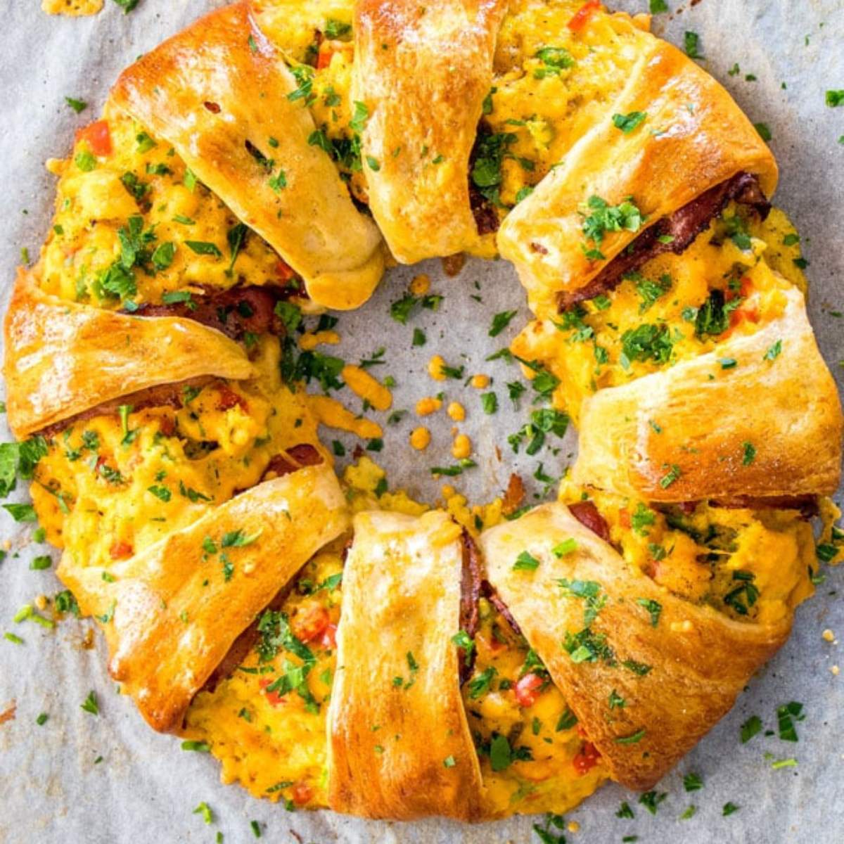  A baked crescent dough ring filled with scrambled eggs, cheese, and bacon, topped with fresh parsley.