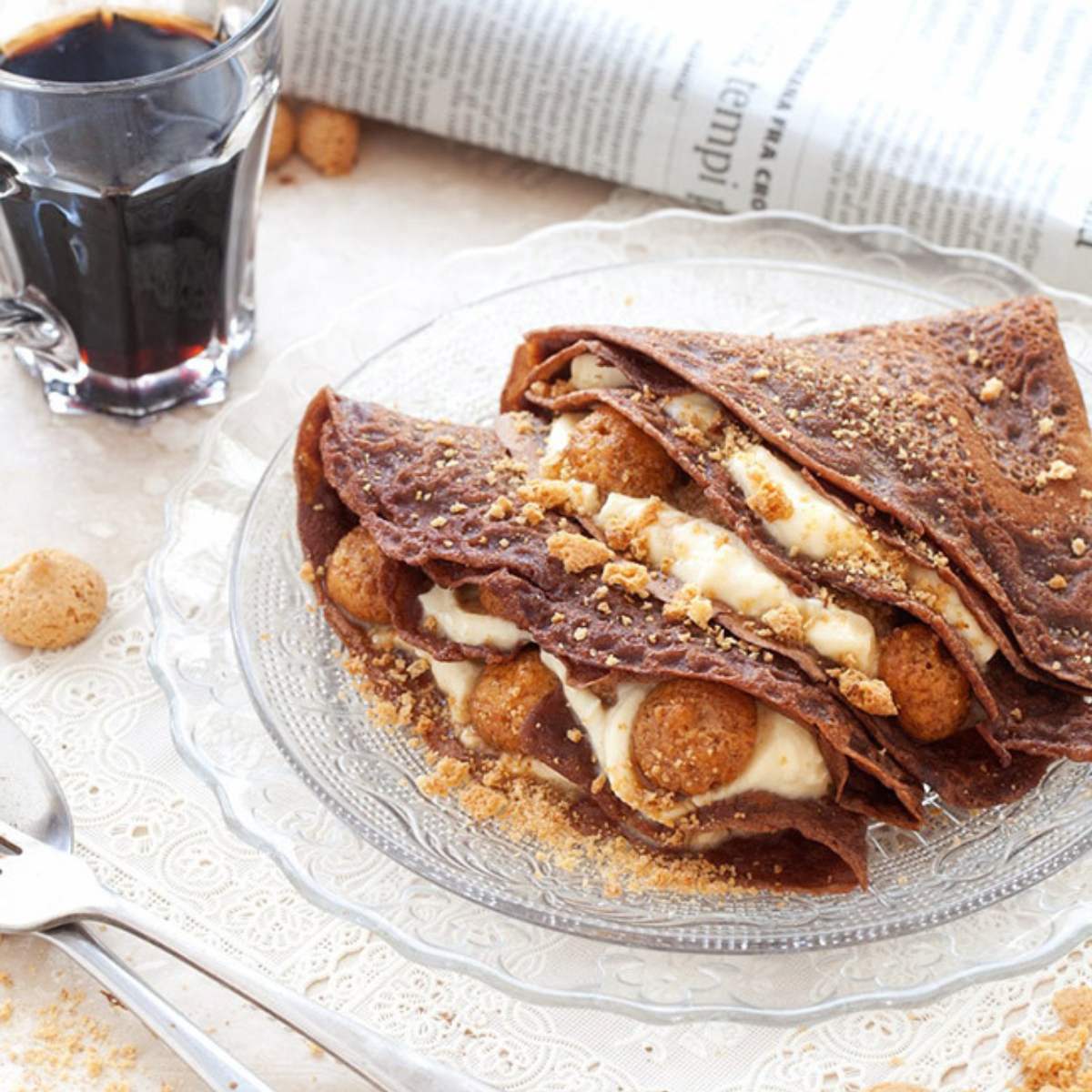 Chocolate crepes filled with a creamy filling, topped with crumbled cookies.