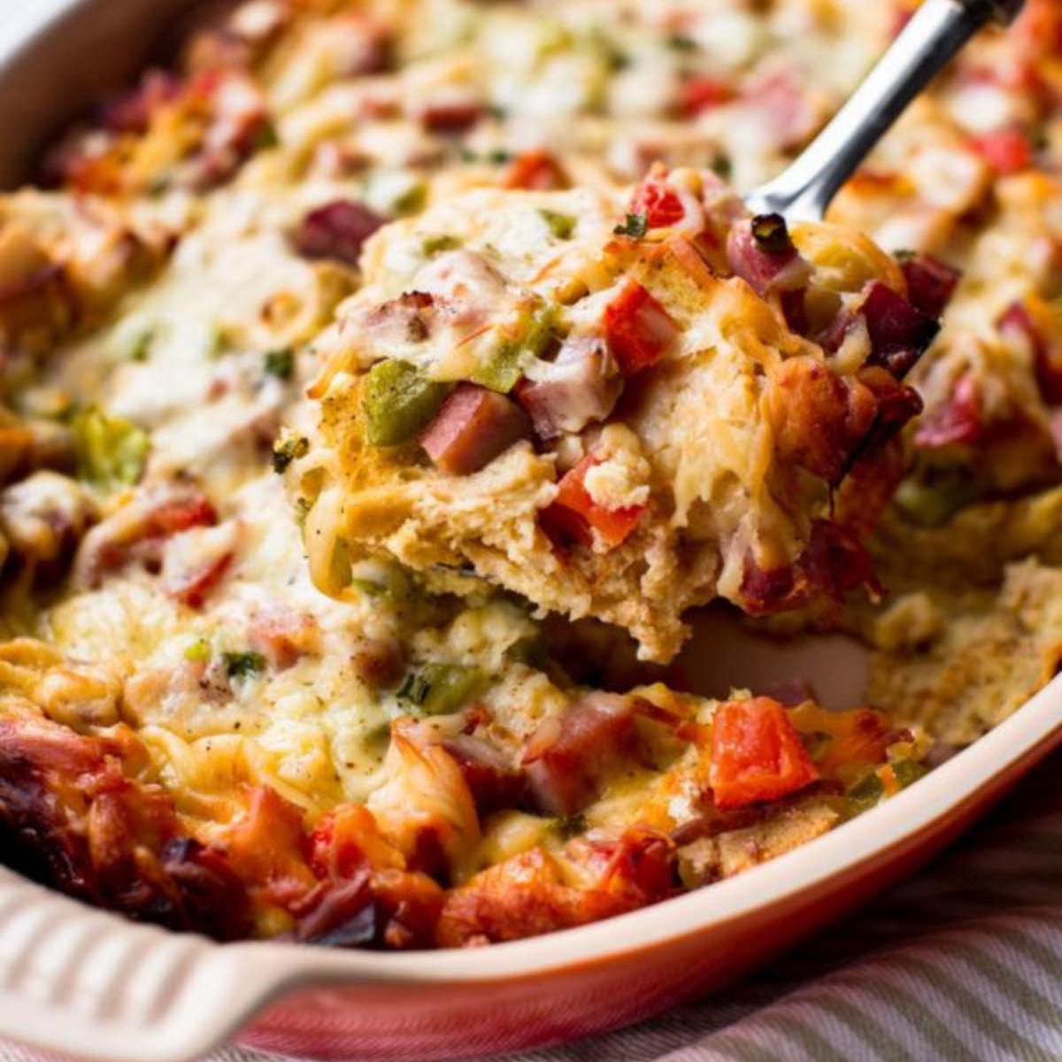 Ham and cheese strata with bread, vegetables, and cheese in a casserole dish.