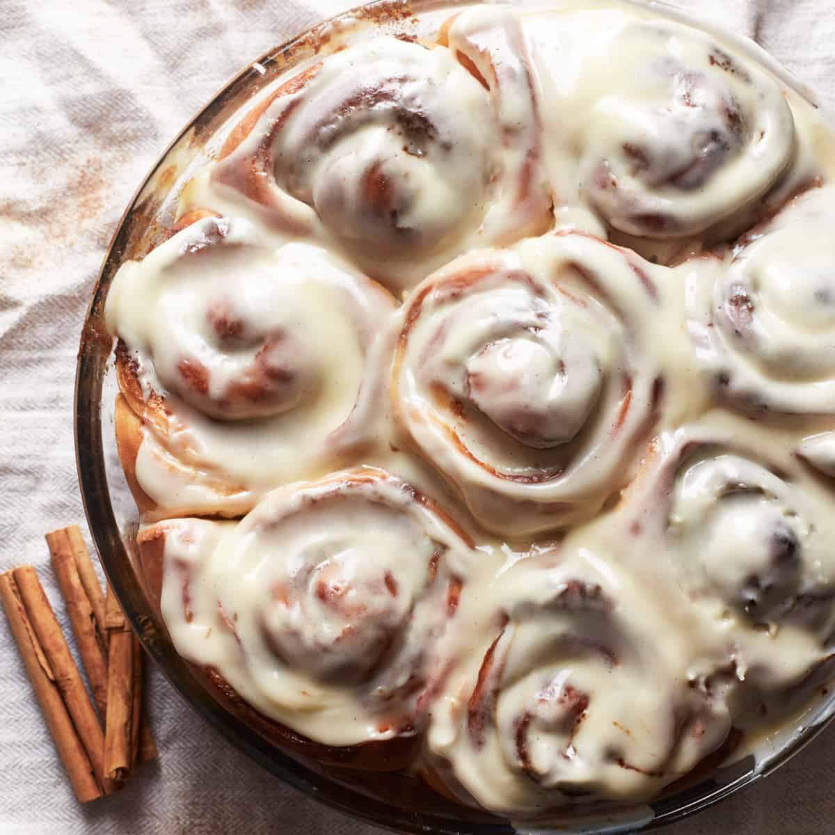 Cinnamon rolls in a glass dish with cream cheese frosting.