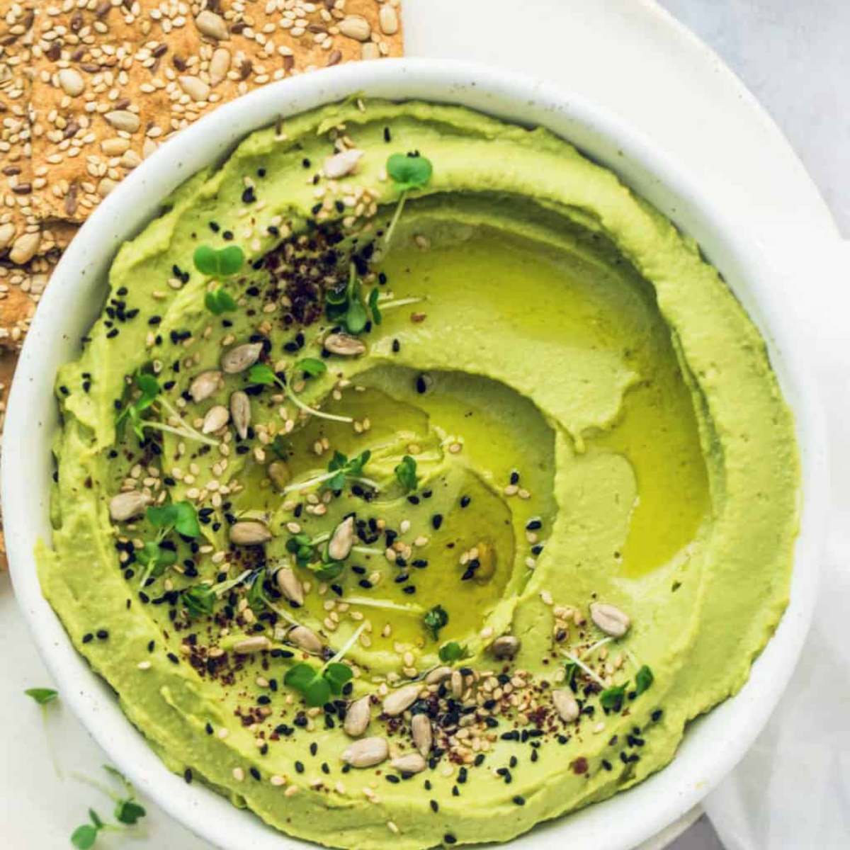 A bowl of creamy avocado hummus with sunflower seeds