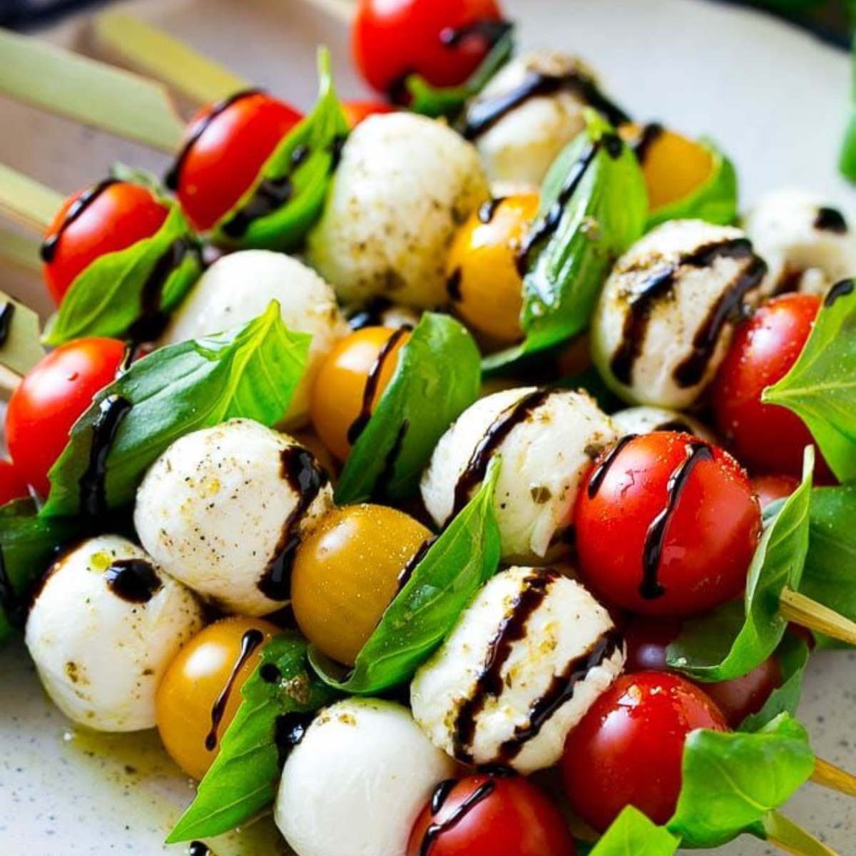  A skewer of cherry tomatoes, mozzarella balls, and fresh basil leaves, drizzled with balsamic glaze.