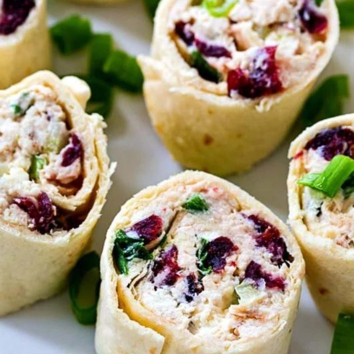 Chicken cranberry pinwheels, made with tortillas filled with a mixture of cream cheese, chicken, cranberries, and green onions.