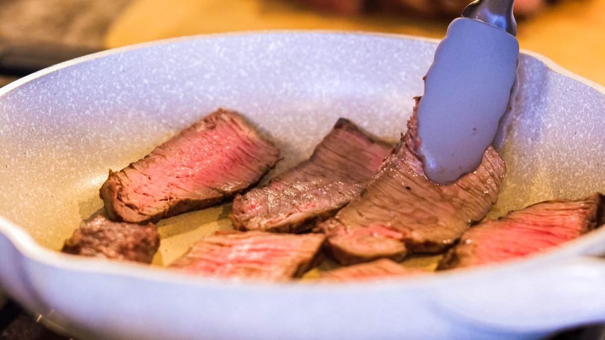 searing steak slices in marbled white pan