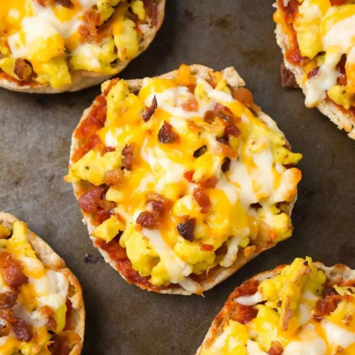 English muffins topped with scrambled eggs, bacon, and melted cheese.