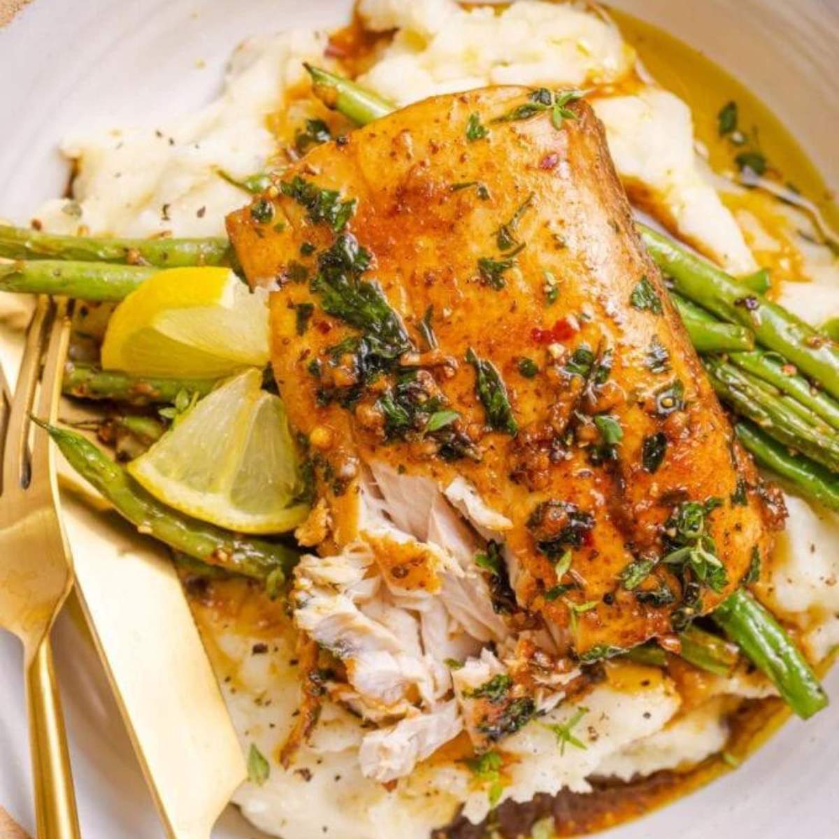  Pan-seared fish with a lemon-herb butter sauce, served with mashed potatoes and green beans.

