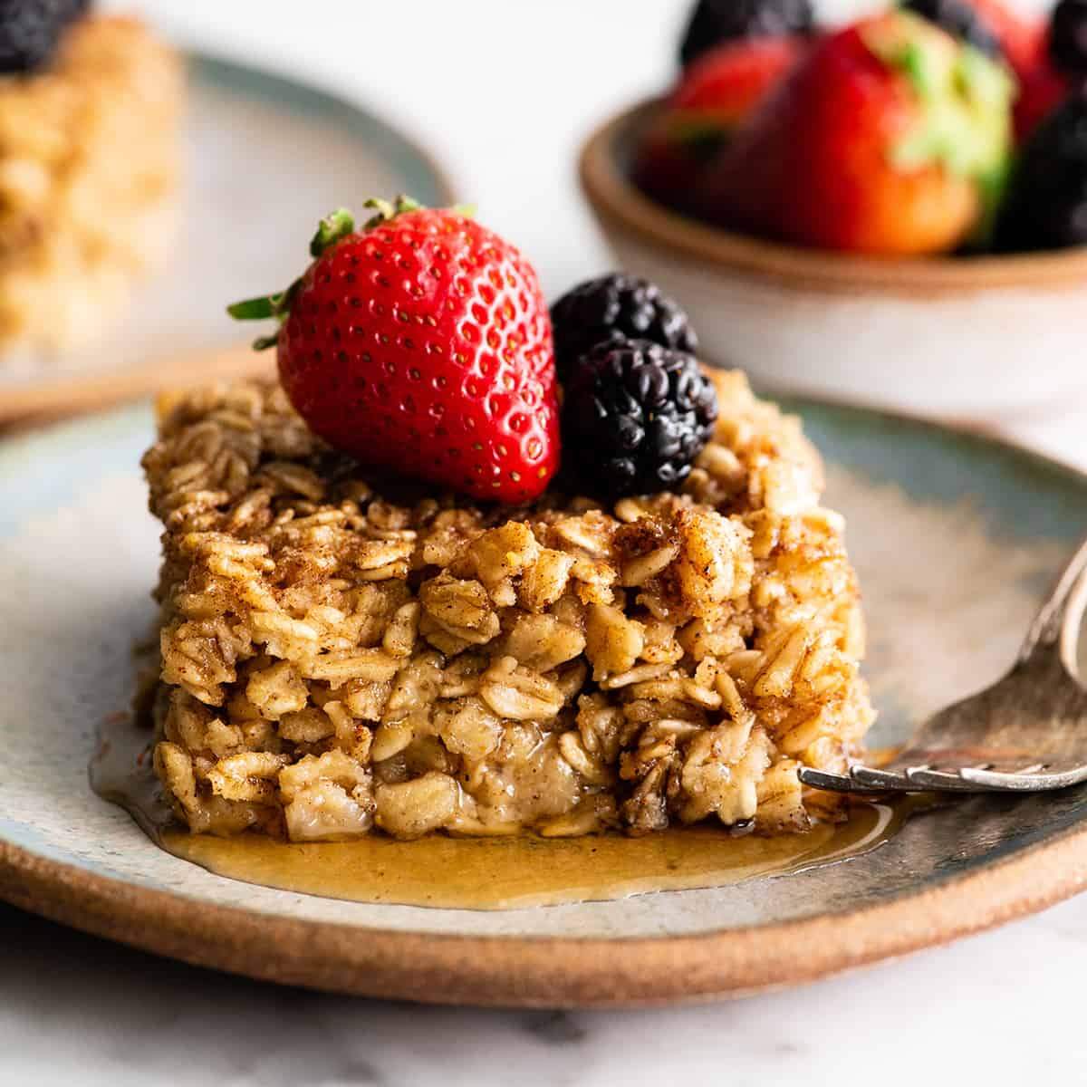 A baked oatmeal square topped with fresh berries and drizzled with maple syrup.