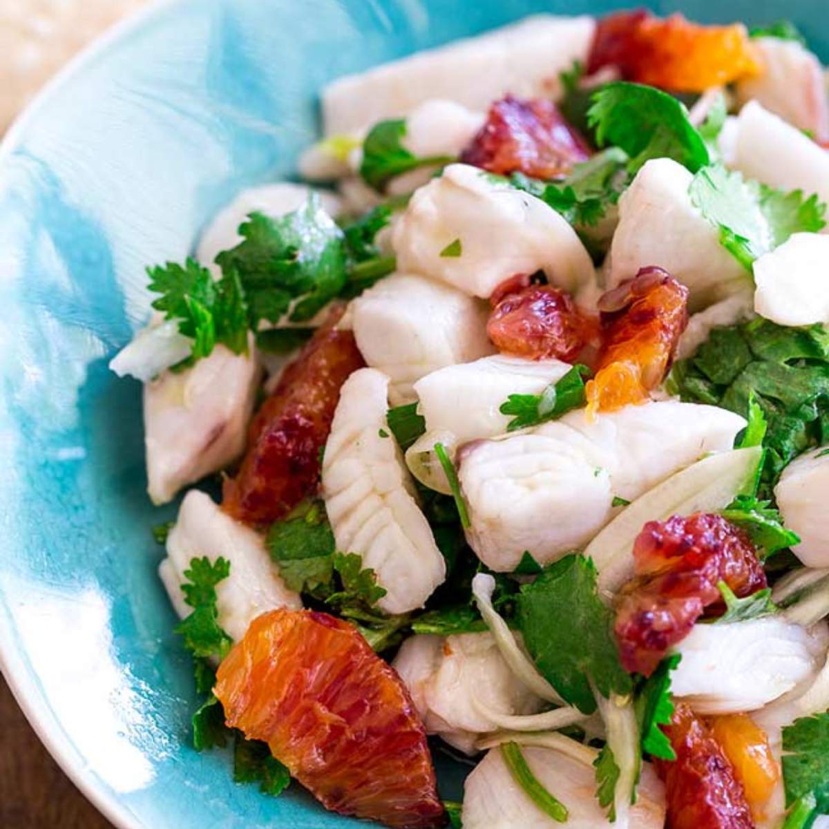 A bowl of ceviche with white fish, blood orange segments, fennel, and cilantro.