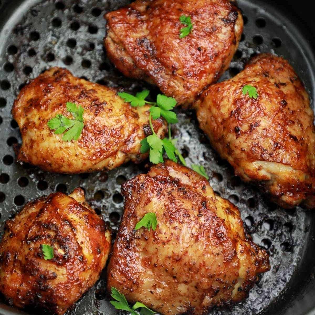 Air fryer chicken thighs cooked to a crispy and golden brown, garnished with fresh parsley.