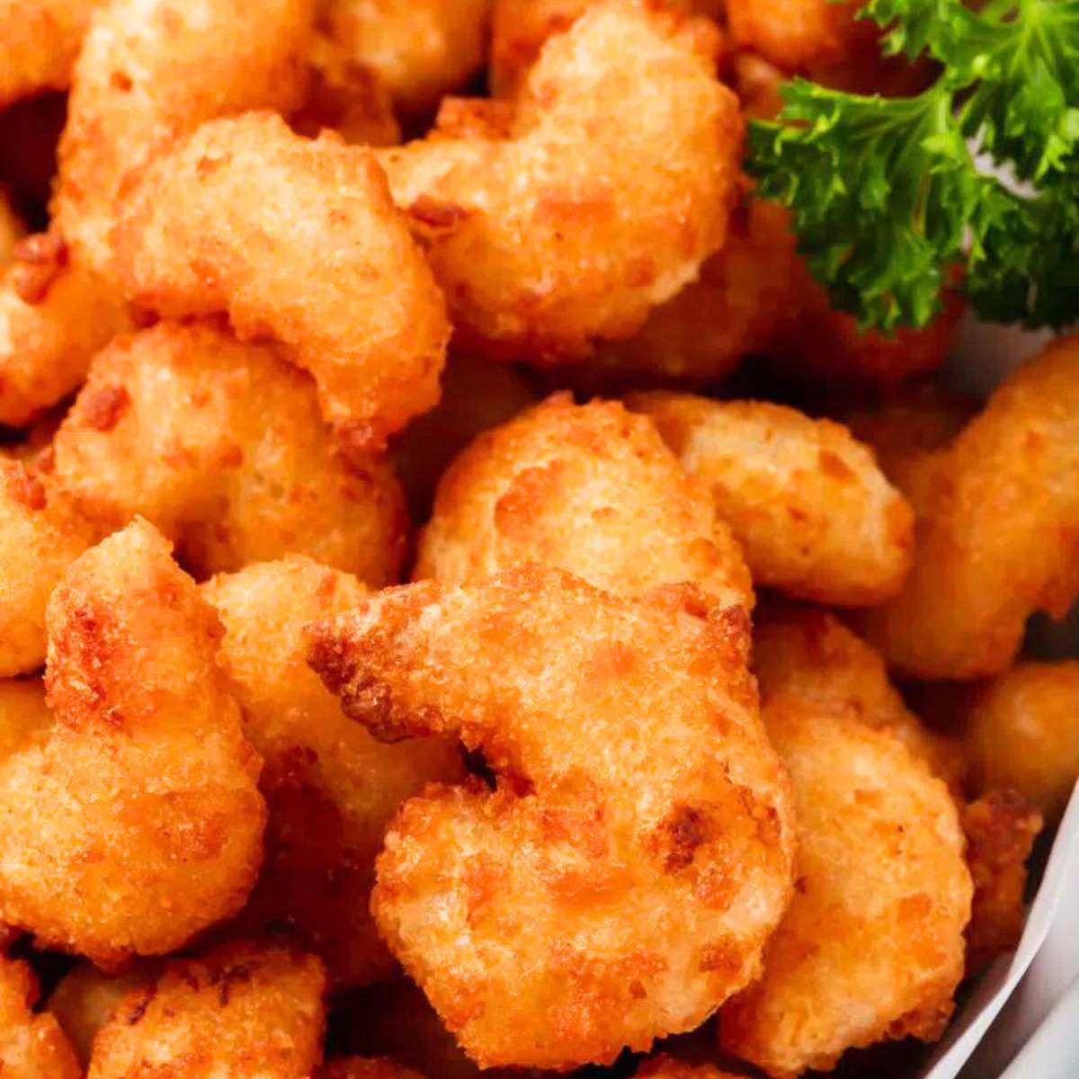 Crispy, golden-brown popcorn chicken, served with a garnish of fresh parsley.