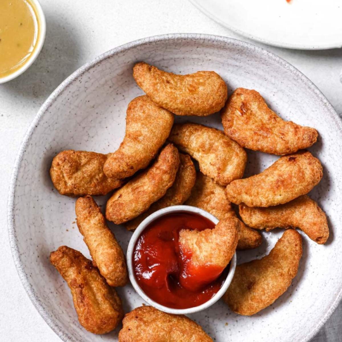 Crispy chicken nuggets served in a bowl with ketchup on the side.