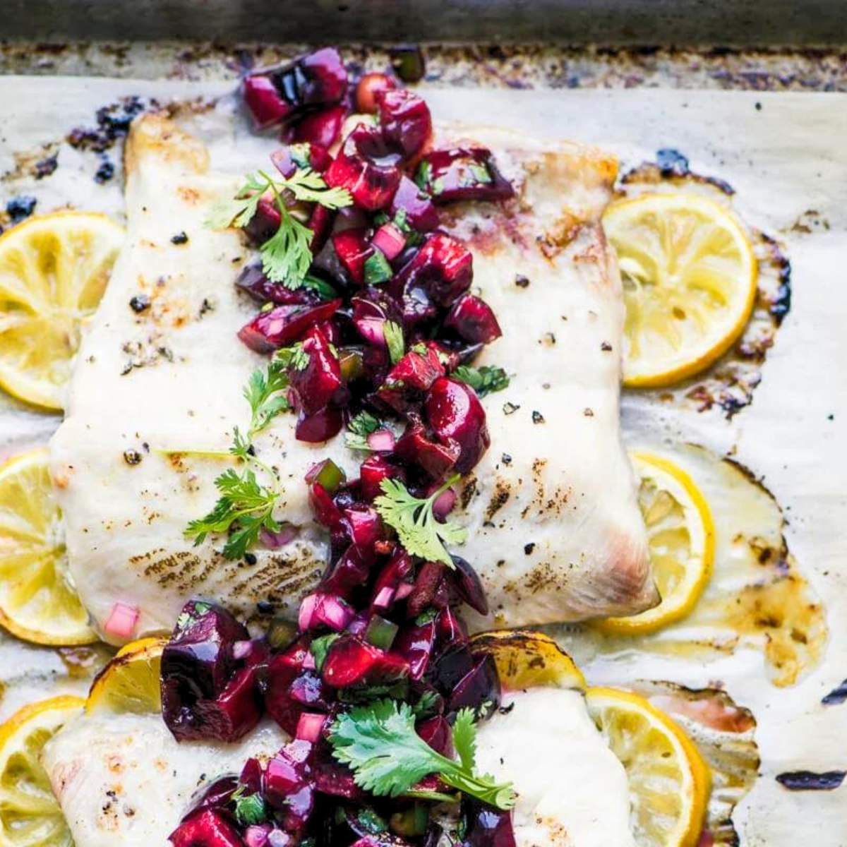 Whitefish fillets topped with a vibrant cherry salsa and lemon slices.