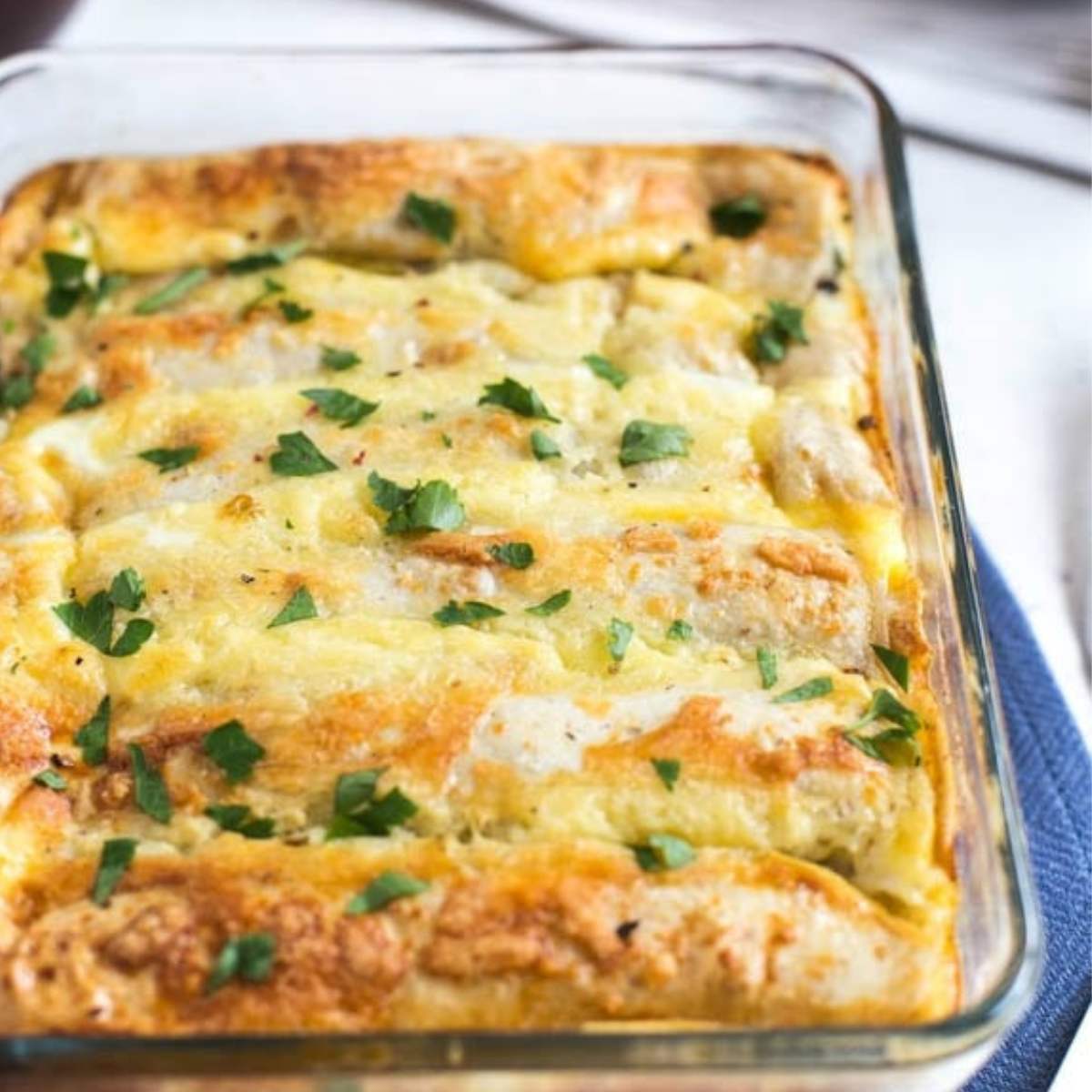 A baked breakfast casserole made with eggs, cheese, and spinach, served in a glass dish and garnished with fresh parsley.