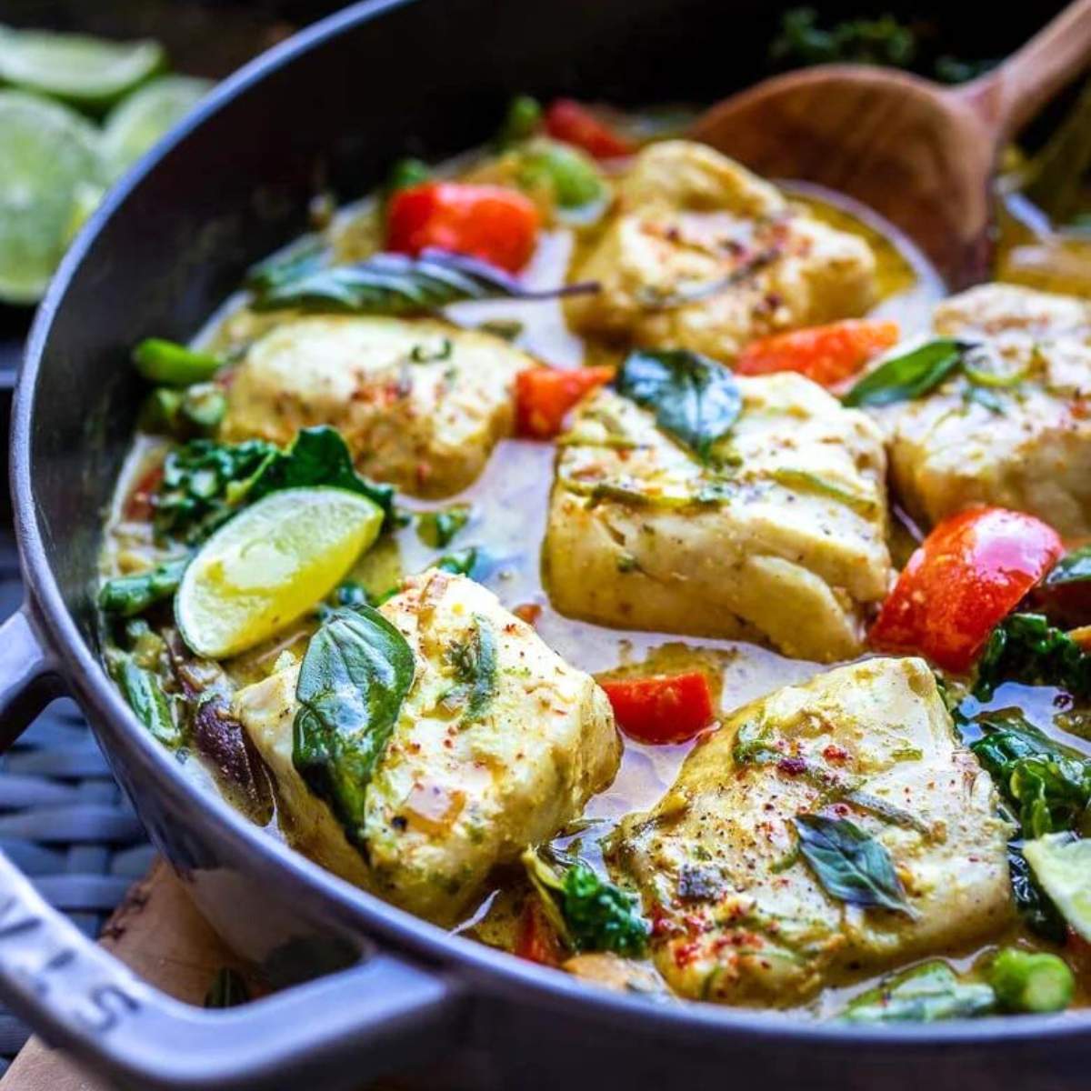  Green curry with white fish, vegetables, and coconut milk served on a skillet.