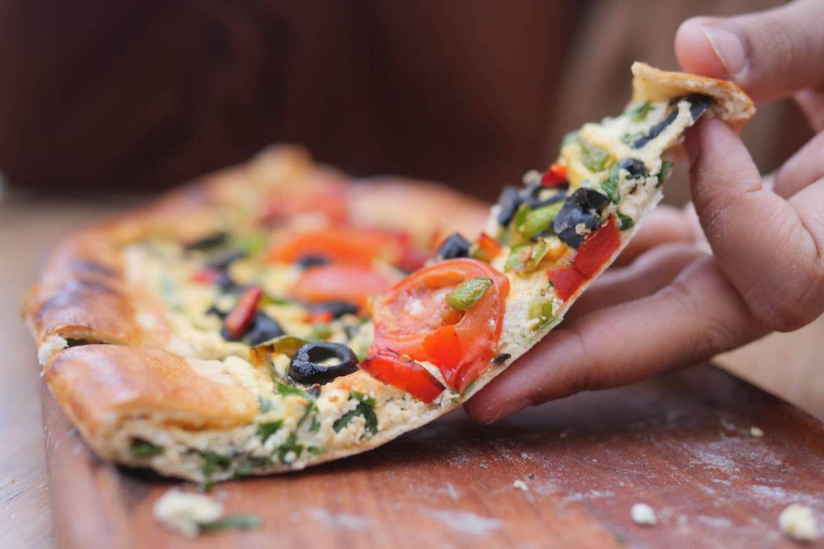 hand picking slice of pizza from a plate