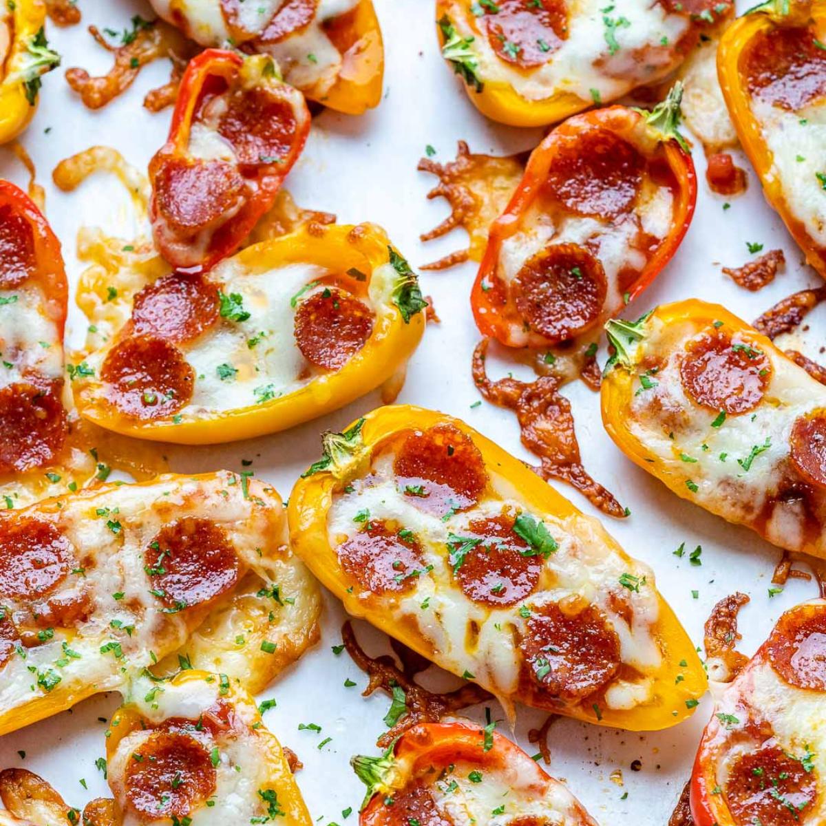 Baked mini peppers filled with pizza sauce, cheese, and pepperoni, served on a baking sheet.