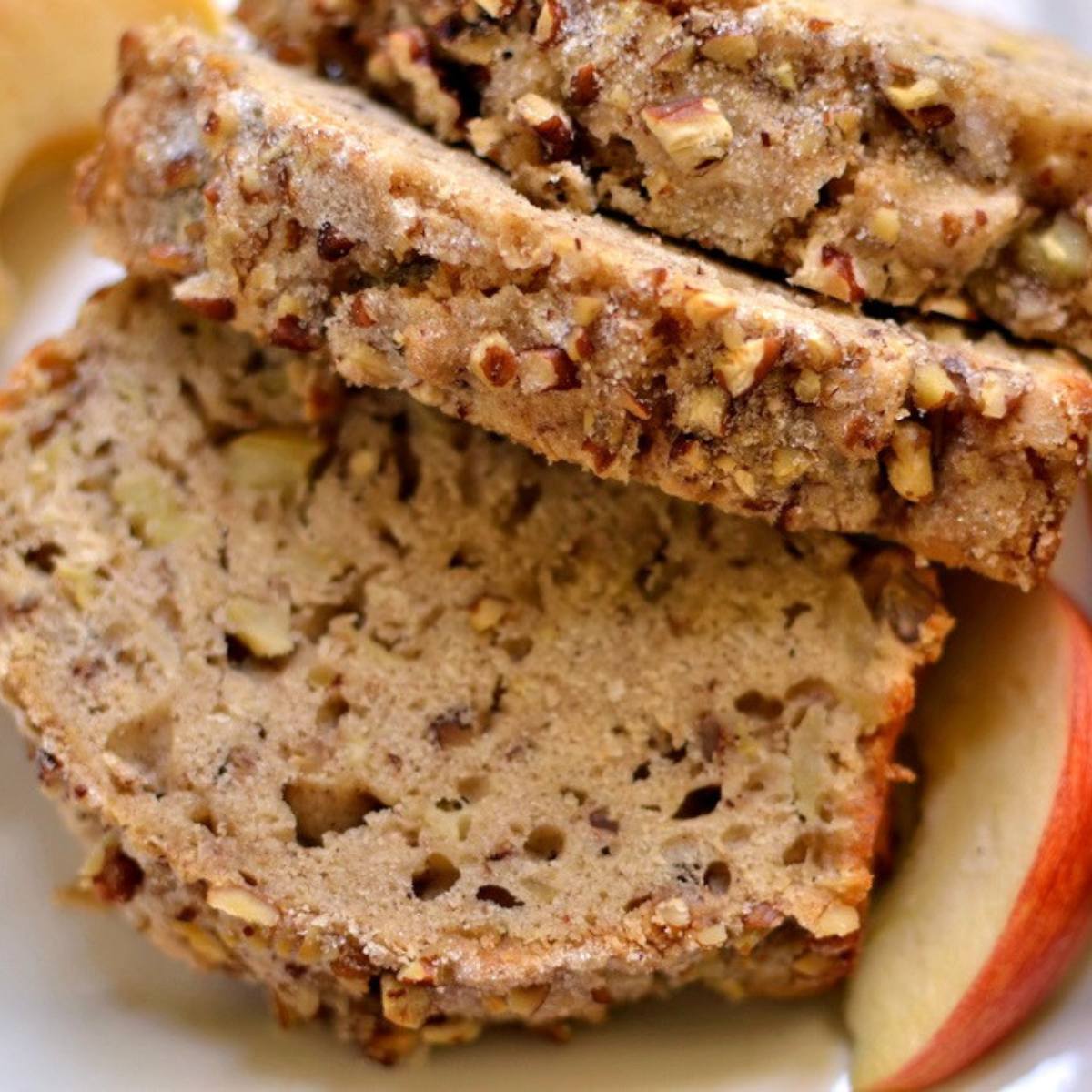 A close-up of slices of apple bread with nuts, sprinkled with powdered sugar.