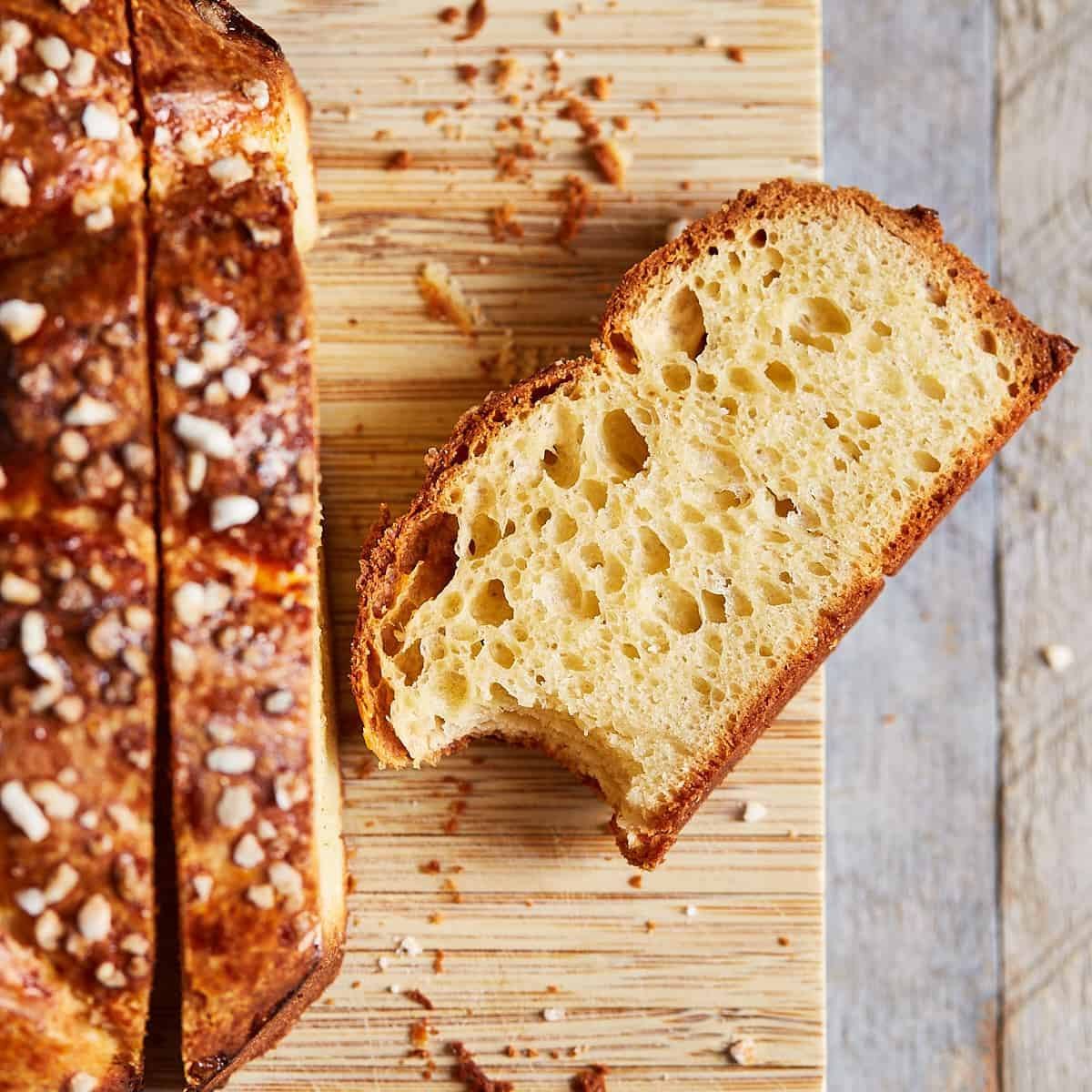 A golden-brown, crusty loaf of bread with a slice cut off, showing the soft, airy crumb inside.