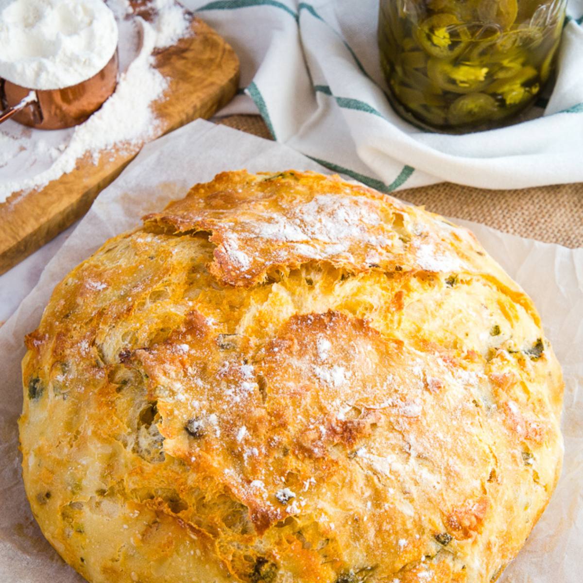 A golden-brown, crusty loaf of bread with a sprinkling of flour on top.