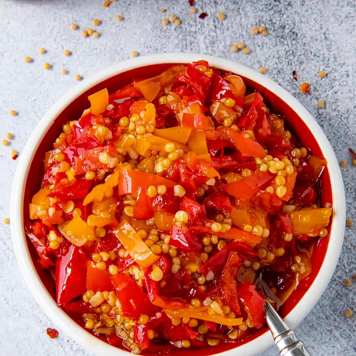 A bowl of sweet chili pepper relish with mustard seeds and garlic.