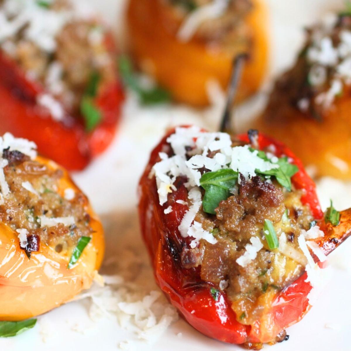 Stuffed mini peppers with a meat and cheese filling, topped with grated Parmesan cheese and fresh basil.