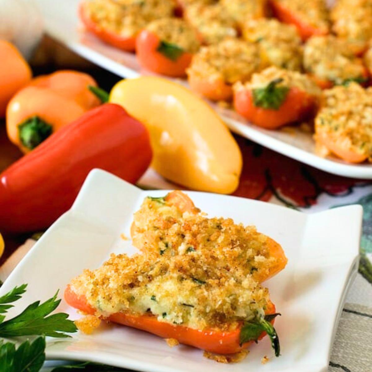 Baked stuffed mini peppers with a creamy filling, topped with breadcrumbs, served on a white plate.