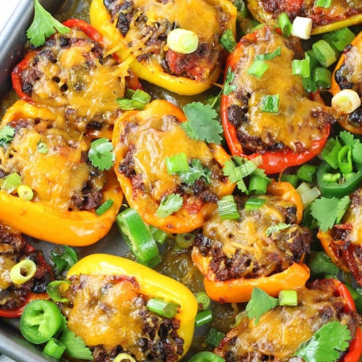 Baked mini peppers stuffed with a Mexican-inspired filling of ground beef, cheese, and spices, topped with chopped green onions and cilantro.