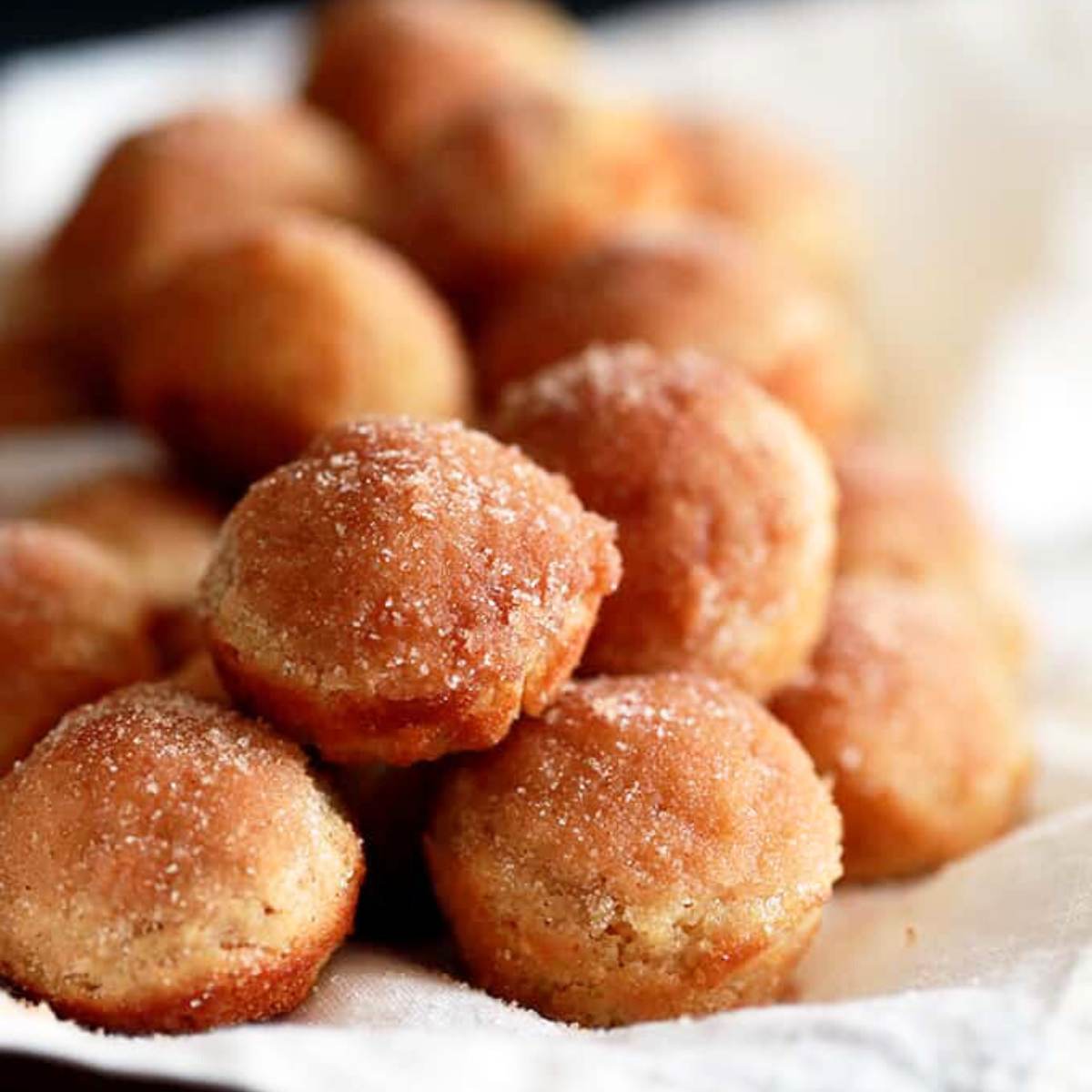 A pile of mini muffins coated in cinnamon sugar.