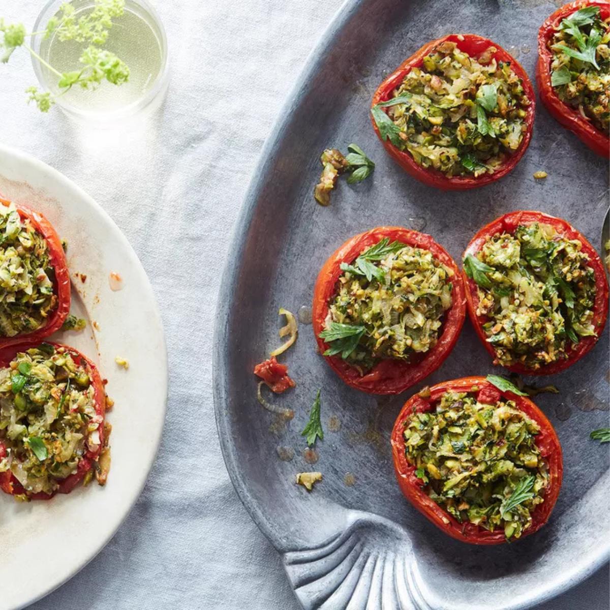 A platter of baked tomatoes filled with a mixture of breadcrumbs, herbs, and cheese.