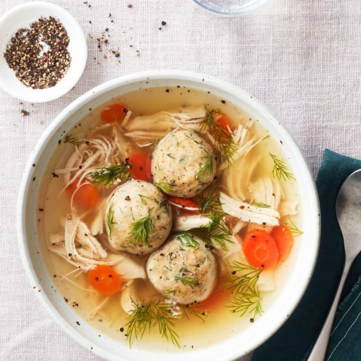 A bowl of classic matzo ball soup with tender chicken, carrots, and fluffy matzo balls.